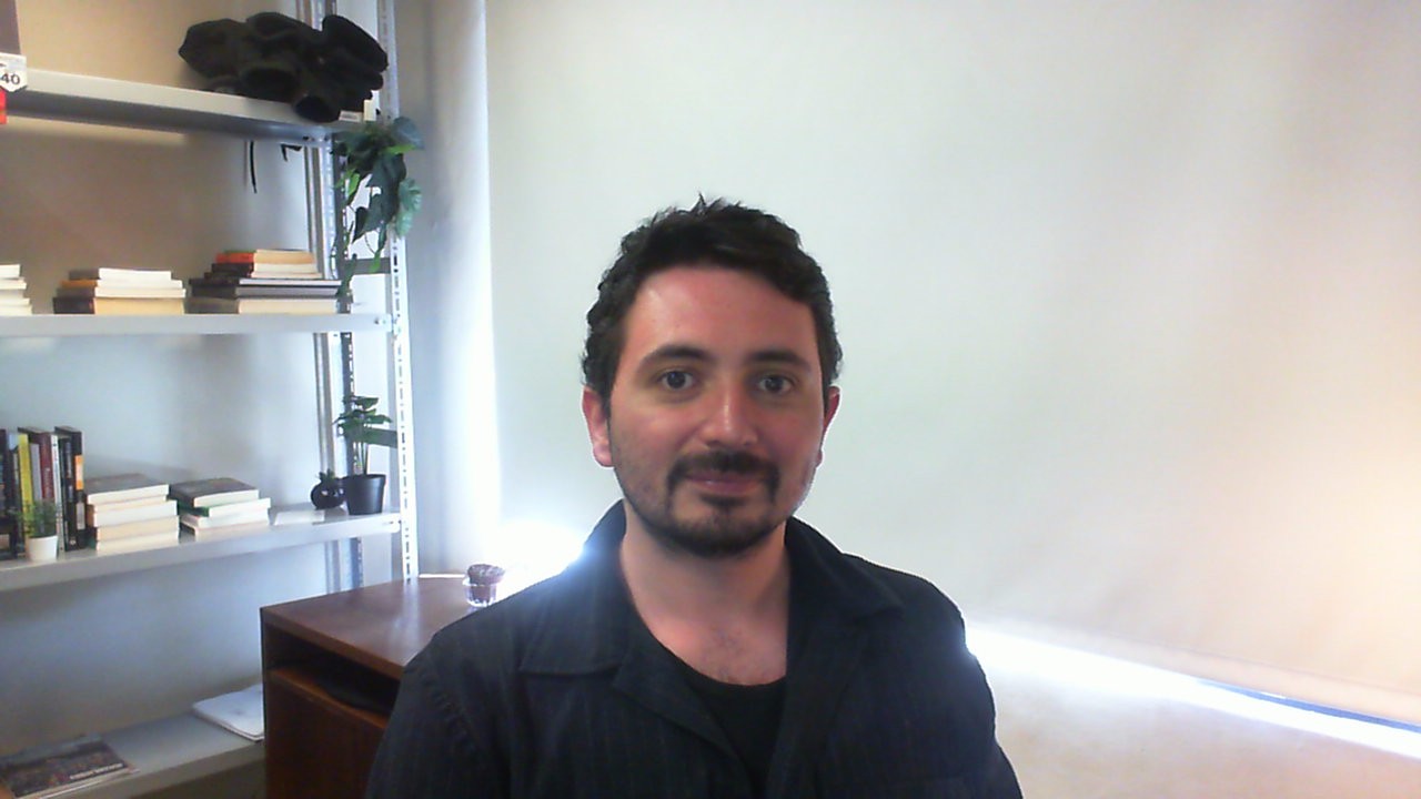 Felipe seated in a desktop environment surrounded by stationary and books